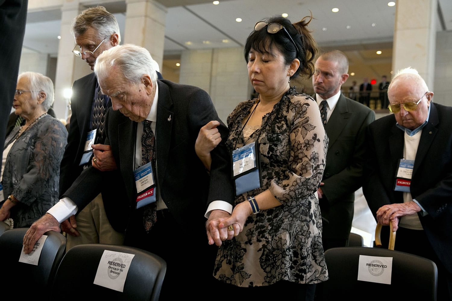 Rand Smith, left, of Mooresville, N.C., helps his father Fighter Ace Air Force Brigadier Gen. Leslie Smith, 96, of Walnut Creek, Calif., to stand with help from Smith's caregiver Taehee Cho, during a prayer at a ceremony awarding the Congressional Gold Medal to the American Fighter Aces, on Wednesday on Capitol Hill in Washington.
