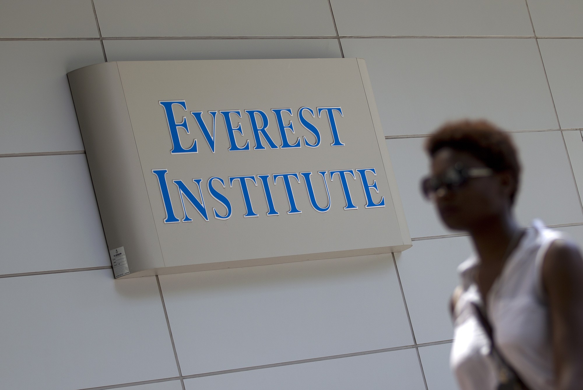 A person walks past an Everest Institute sign on an office building in Silver Spring, Md..