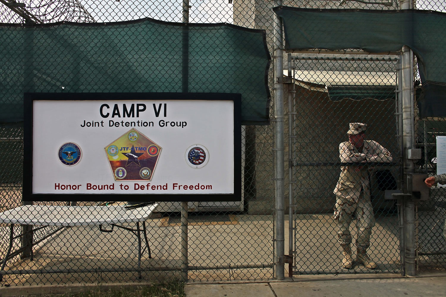 In this photo taken Tuesday May 12, 2009, and reviewed by the U.S. military, a soldier stands guard at the front gate entrance to Guantanamo's Camp 6 maximum-security detention facility, at Guantanamo Bay U.S. Naval Base, Cuba. The U.S.