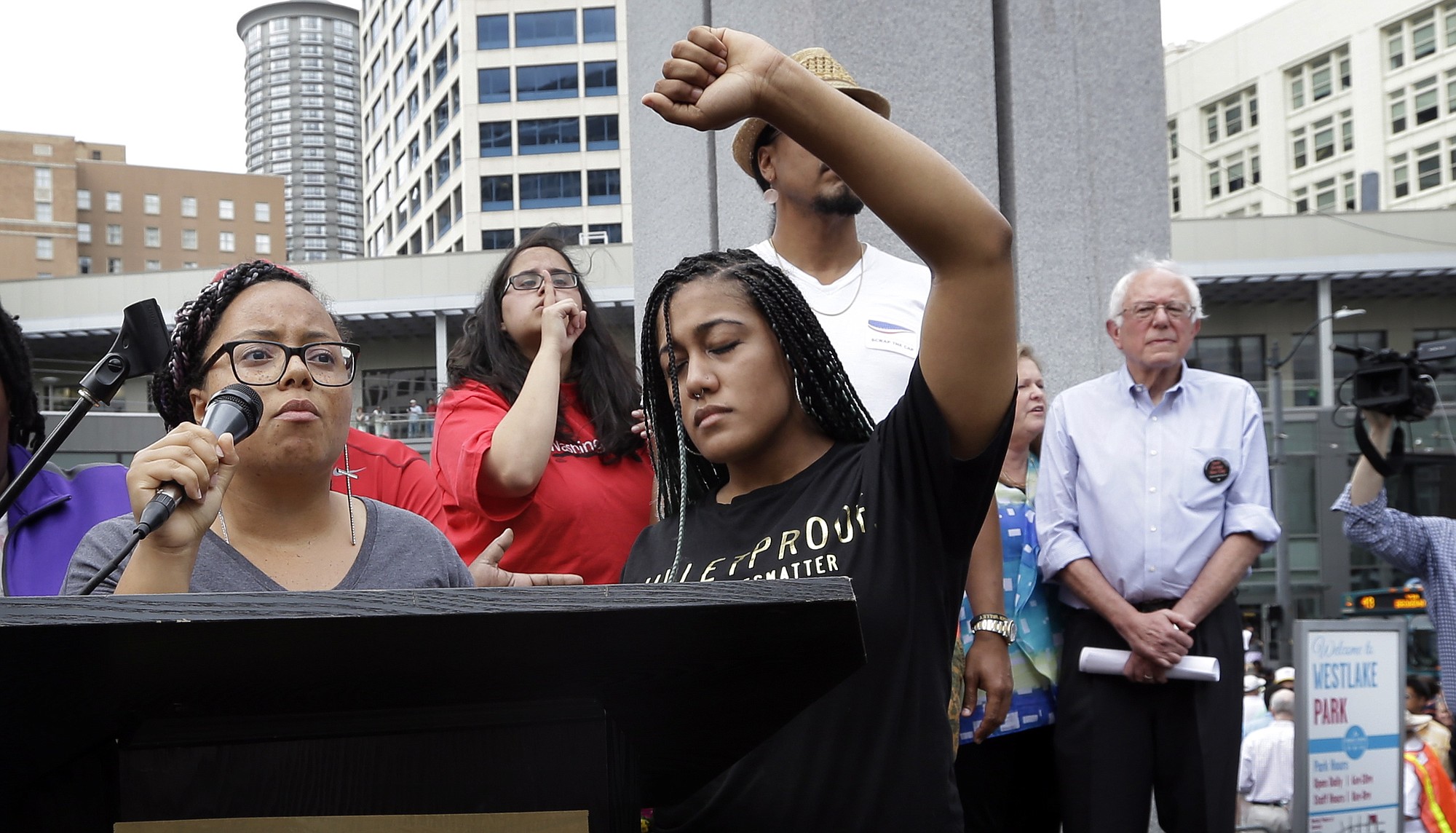 Marissa Johnson, left, speaks as Mara Jacqueline Willaford holds her fist overhead and Democratic presidential candidate Sen. Bernie Sanders, I-Vt., stands nearby as the two women take over the microphone at a rally Saturday in downtown Seattle. The women, co-founders of the Seattle chapter of Black Lives Matter, took over the microphone and refused to relinquish it.