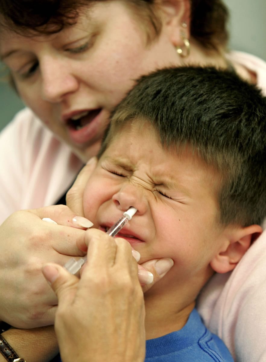 Associated Press files
Eric Krex, 6, held by his mother, Margaret, reacts as a nurse gives him a FluMist influenza vaccination.