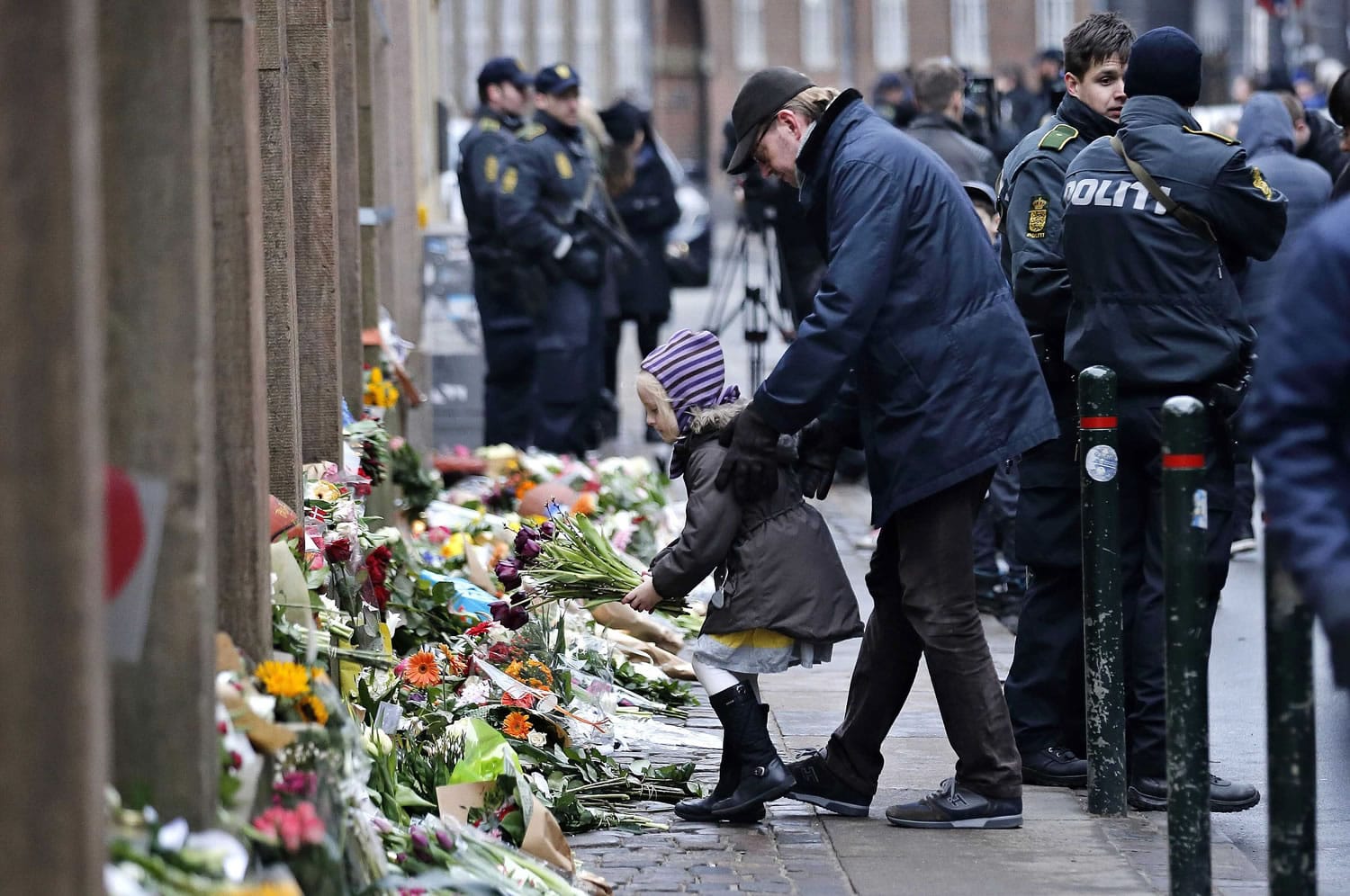 People laying flowers outside a synagogue Sunday where an attack took place in Copenhagen. Danish police shot and killed a man early Sunday suspected of carrying out shooting attacks at a free speech event and then at a Copenhagen synagogue, killing a Danish documentary filmmaker and a member of the Scandinavian country's Jewish community.