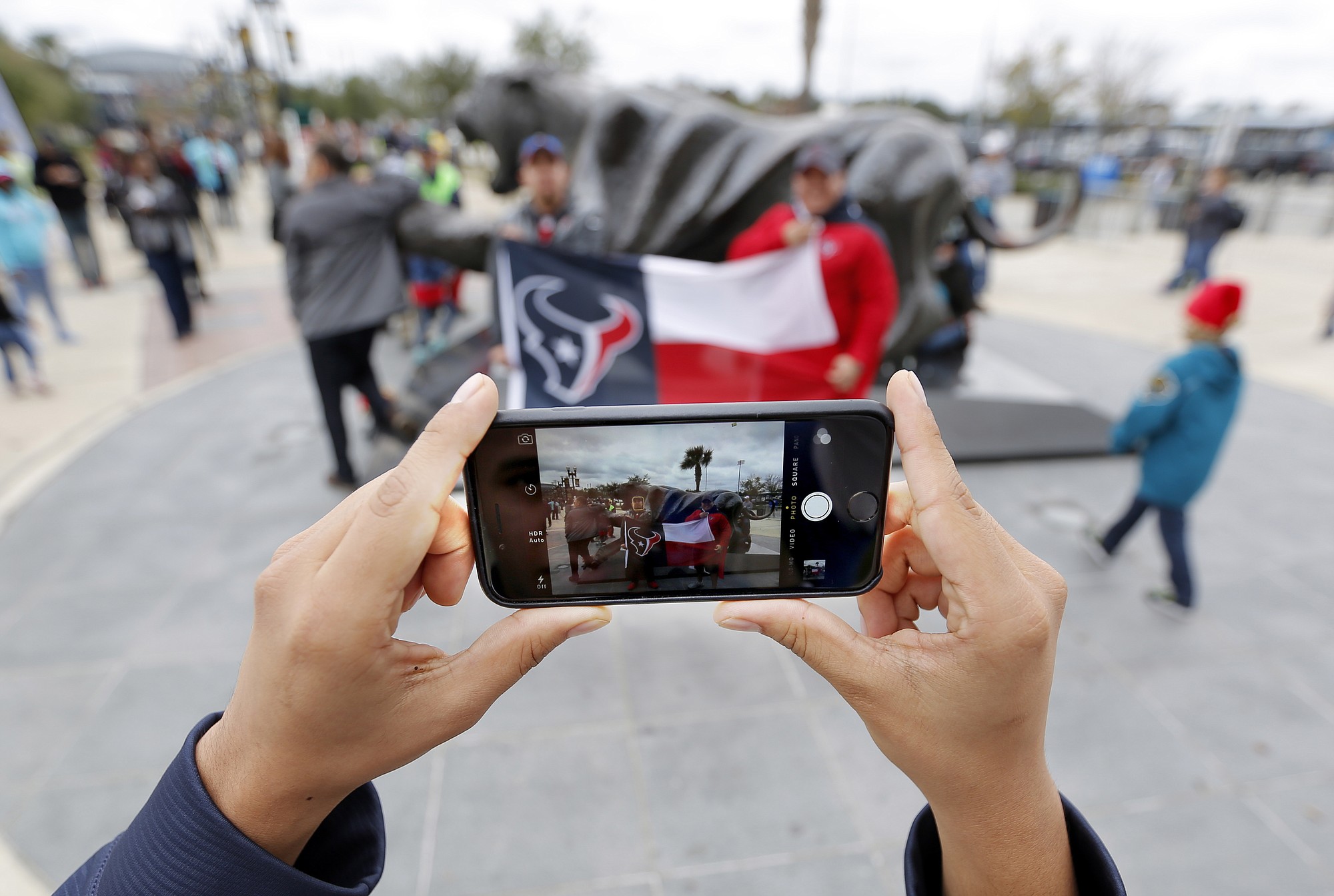 Houston Texans fan Erick Salgado takes a photo with his cellphone of his brother Andres Salgado, left, and his cousin Victor Ticas, right, Dec. 7 before the start of a football game in Jacksonville, Fla.