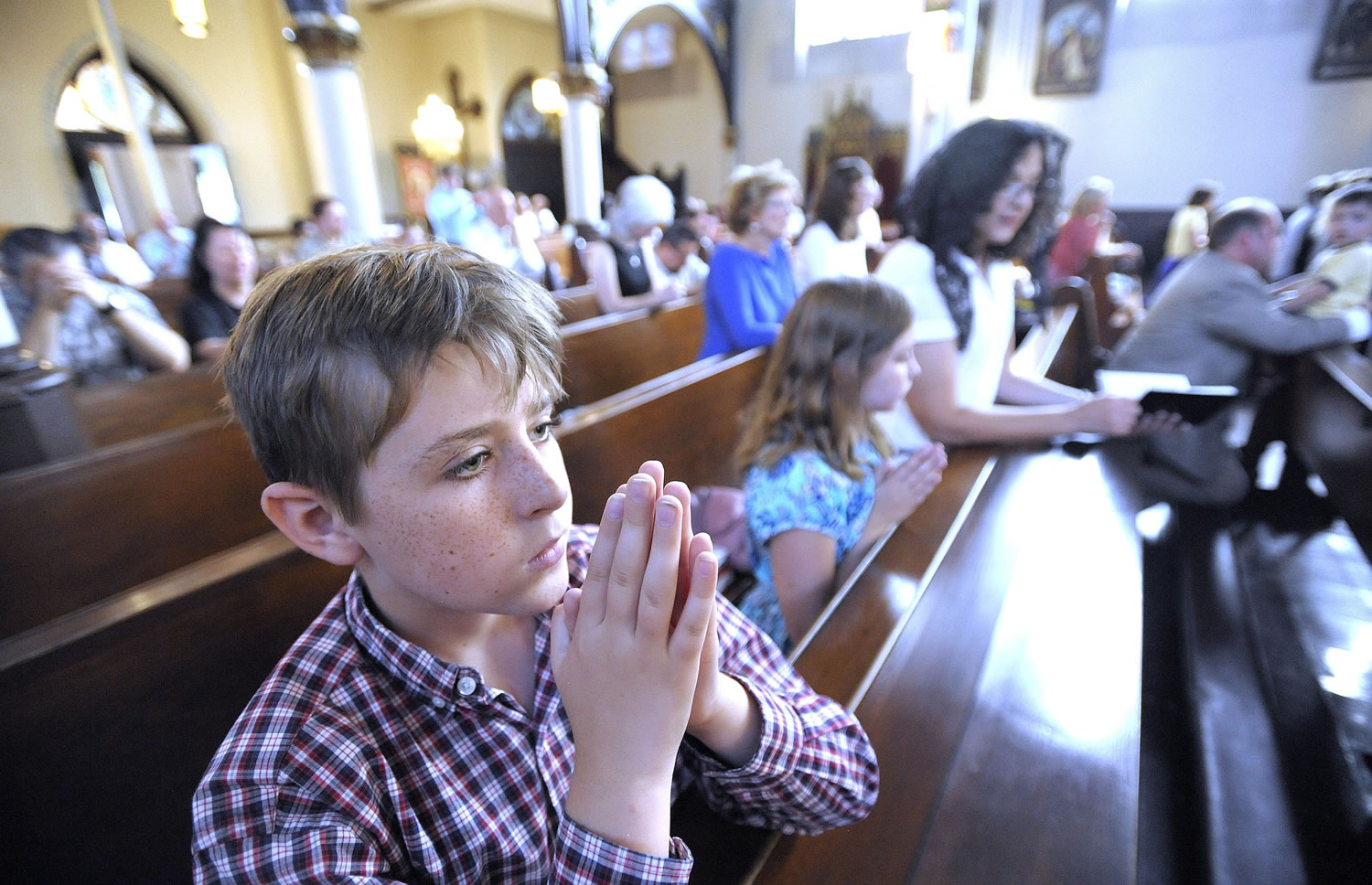 Thomas Carey, left, his sister Charlotte, center, and mother Anita, right, kneel Saturday as they pray during Mass at Saint Joseph Catholic Church in Detroit.