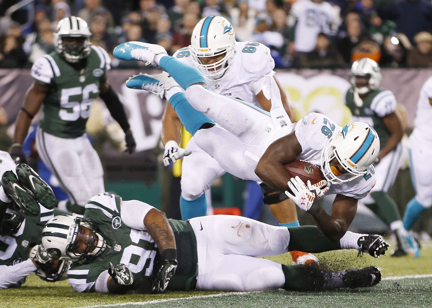 Miami Dolphins running back Lamar Miller (26) leaps over New York Jets defensive end Sheldon Richardson (91) for a touchdown during the fourth quarter Monday, Dec. 1, 2014, in East Rutherford, N.J.