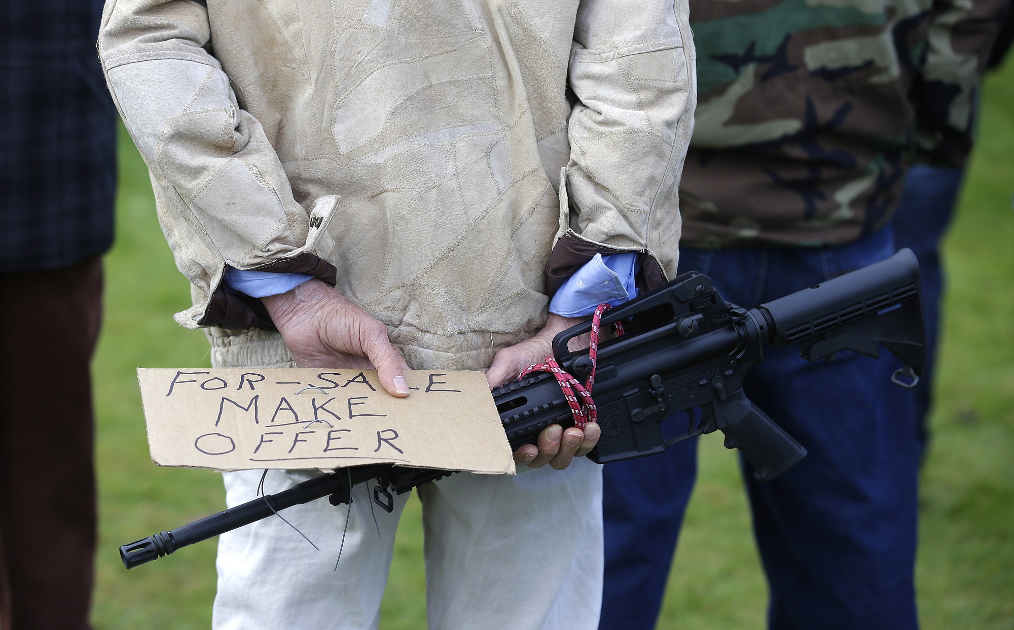 Ralph Eaton of Tacoma holds an Olympic Arms semi-automatic rifle and a sign that reads &quot;For-Sale Make Offer&quot; as he attends a gun rights rally at the Capitol in Olympia.