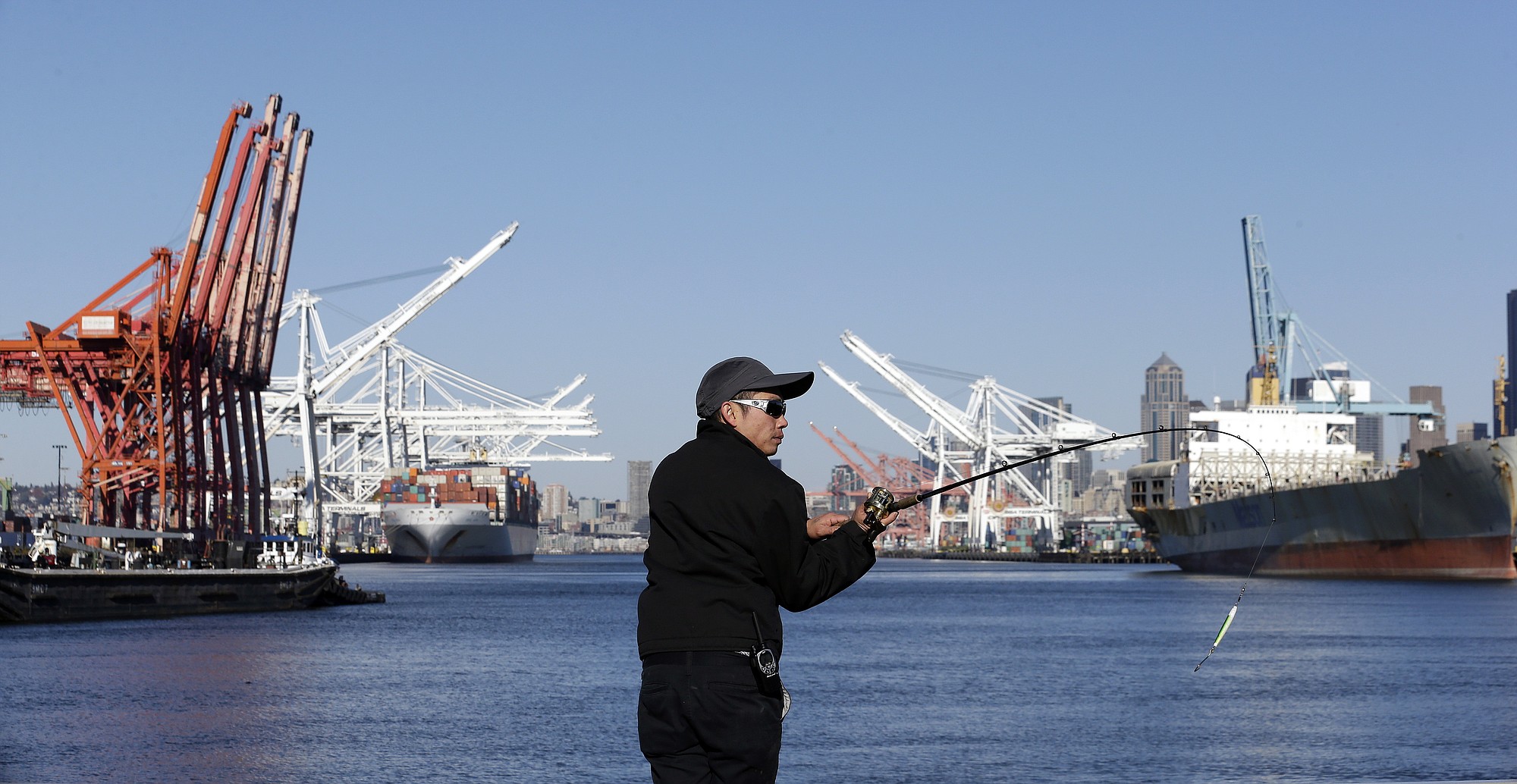 A fisherman readies a cast into the Duwamish Waterway in view of container ships moored at the Port of Seattle's seaport just south of downtown. The U.S.