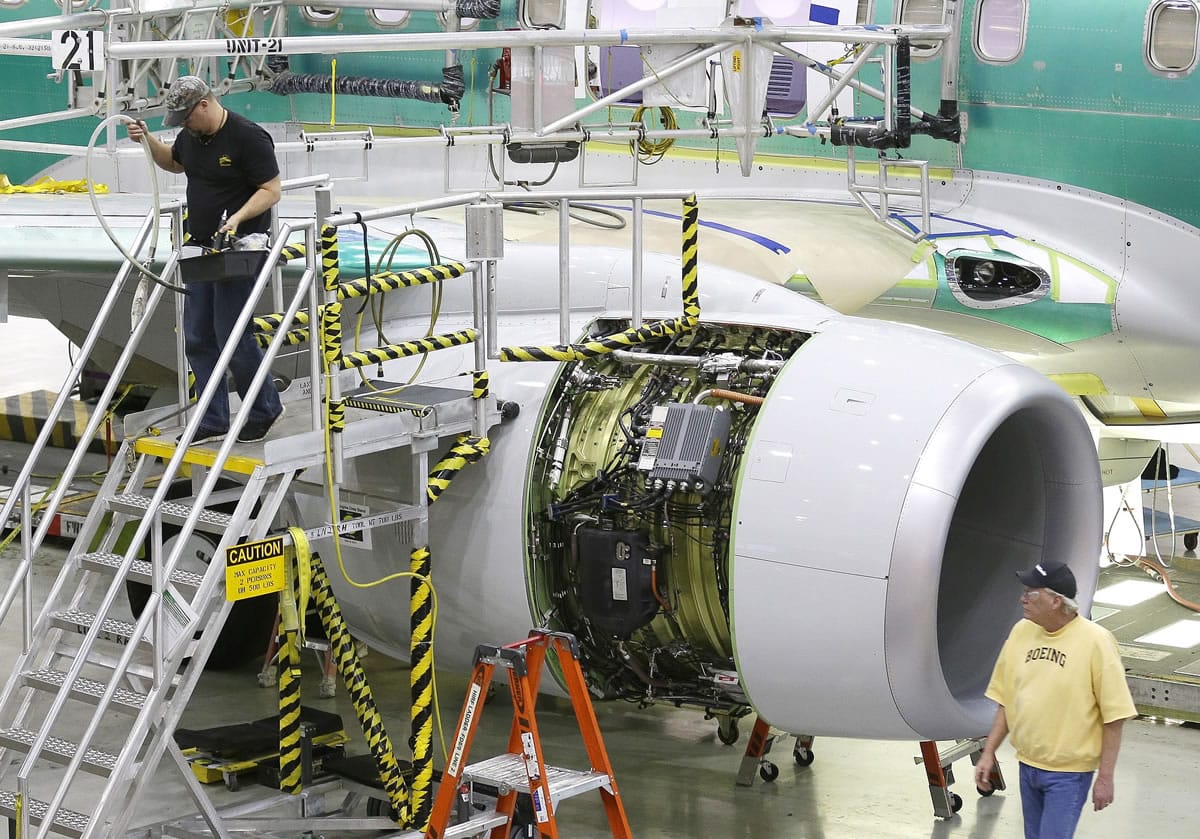 Workers walk near an engine of a Boeing airplane being assembled at Boeing's 737 facility in Renton.