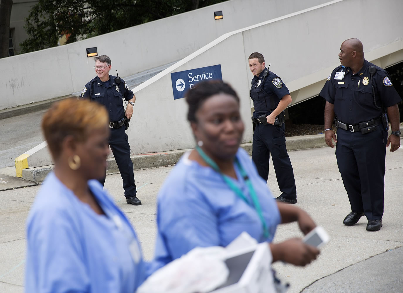 Hospital workers pass police officers guarding an entrance to Emory University Hospital after an ambulance arrived transporting an American that was infected with the Ebola virus, Saturday in Atlanta.  A specially outfitted plane carrying Dr. Kent Brantly from West Africa  arrived at a military base in Georgia. Brantly was taken to the Atlanta hospital.
