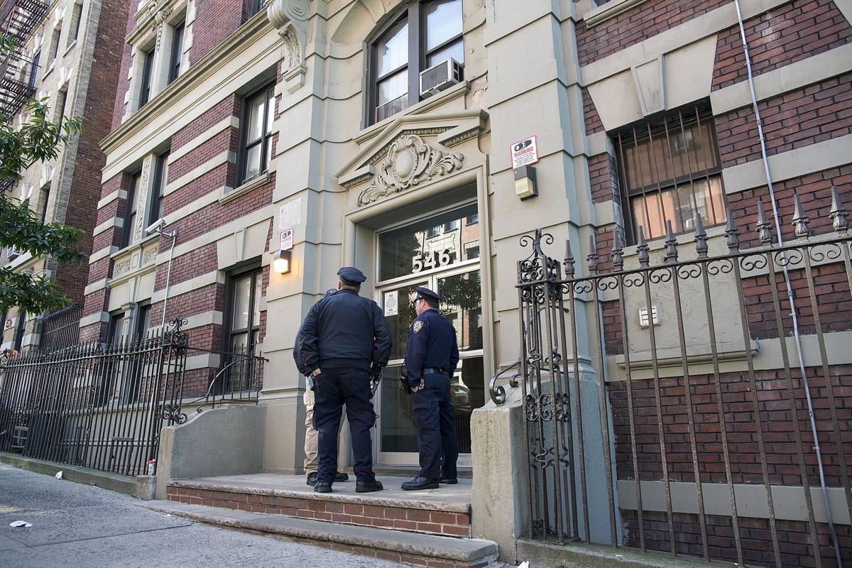New York City police officers stand at the building entrance of Ebola patient Dr. Craig Spencer in New York on Saturday. Spencer remained in stable condition while isolated in a hospital, talking by cellphone to his family and assisting disease detectives who are accounting for his every movement since arriving in New York from Guinea via Europe on Oct.