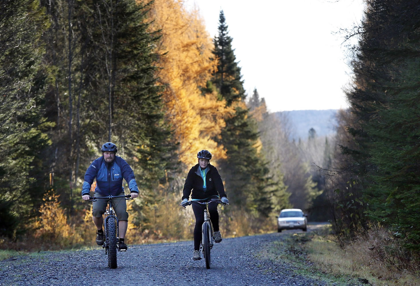 Nurse Kaci Hickox, right, and her boyfriend, Ted Wilbur are followed by a Maine State Trooper as they ride bikes on a trail near their home in Fort Kent, Maine, on Thursday.