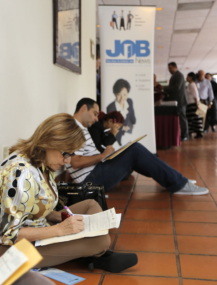 Job seekers fill out job applications at a job fair in Miami Lakes, Fla.