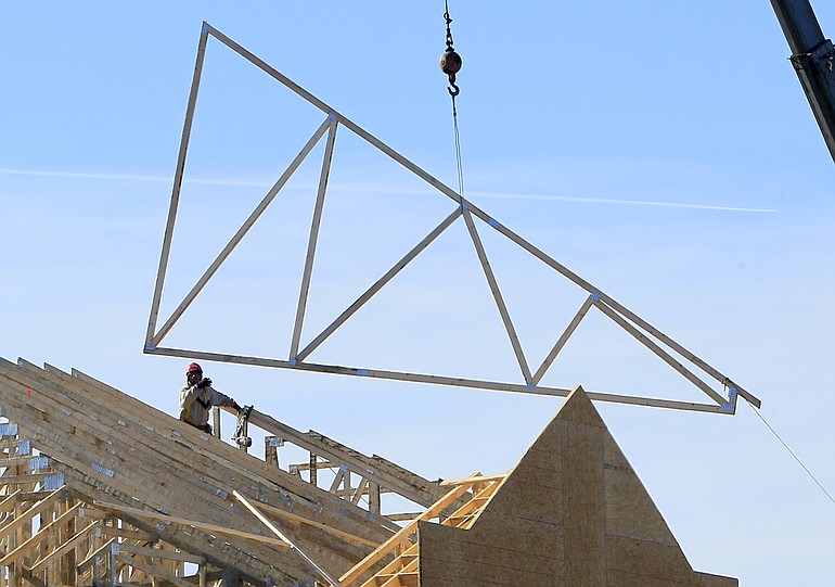 A construction worker guides a truss into position at a construction site Thursday in Dayton, Ohio.