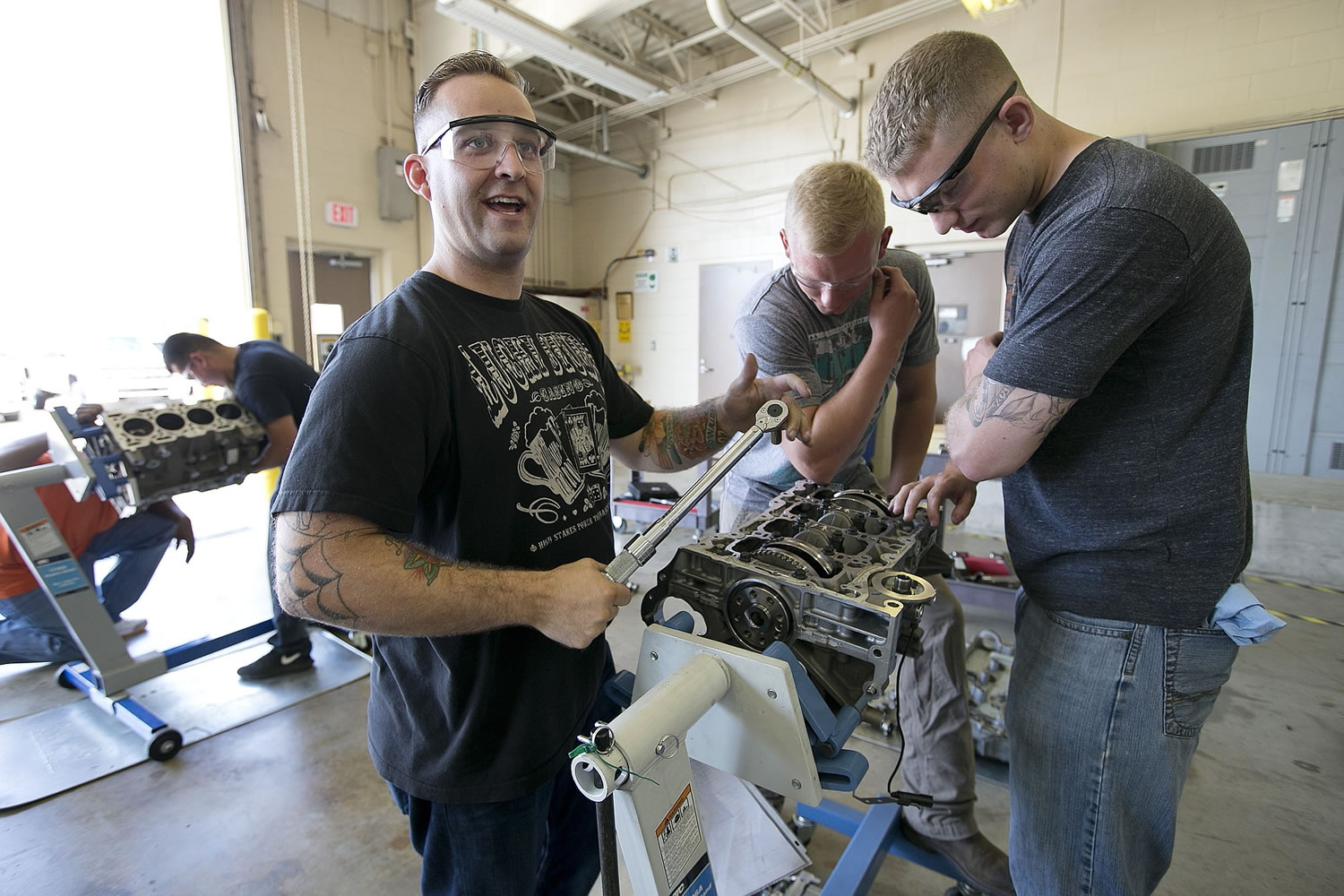 Sgt. Garret Baganz, from left, Spc. Tyler Sonsoucie and Spc. Ian Sokol work on a ecotech engine during a June 18 automotive skills class at Fort Hood, Texas. The men are participants in Shifting Gears, a program sponsored by General Motors that teaches automotive skills and tries to match participants with dealerships around the country. The Labor Department reported Friday that U.S. employers added 215,000 jobs in July.