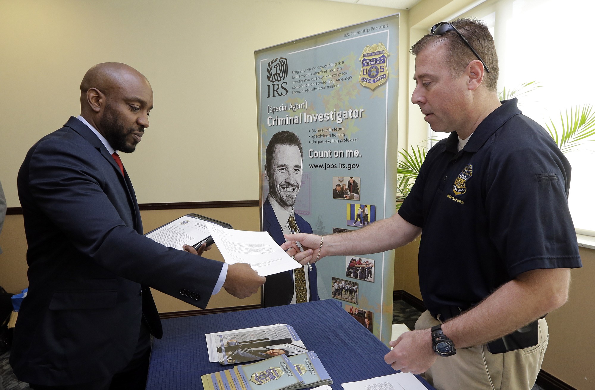 In this Feb. 6, 2015 photo, U.S. Marine Corps Veteran Arlington Robertson, of Fort Lauderdale, left, hands his resume to an Internal Revenue Service Special agent Feb. 6 at the annual Veterans Career and Resource Fair in Miami. The Labor Department reported Friday that employers added 295,000 jobs in February.