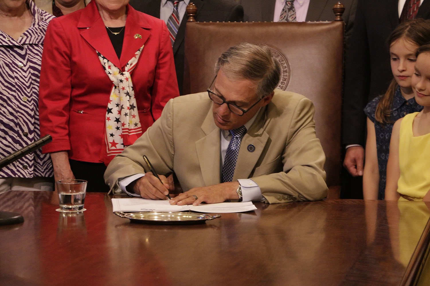 Gov. Jay Inslee signs a bill cutting tuition at the state's colleges and universities Monday in Olympia. National experts on college tuition have called Washington's tuition cut a rare move that could influence other states.
