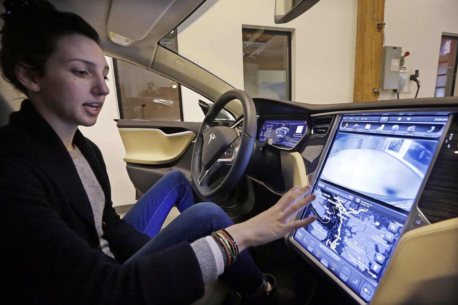 Tesla product specialist Kat Brand explains the control panel on the electric car at a dealership for the vehicle Wednesday in Seattle.