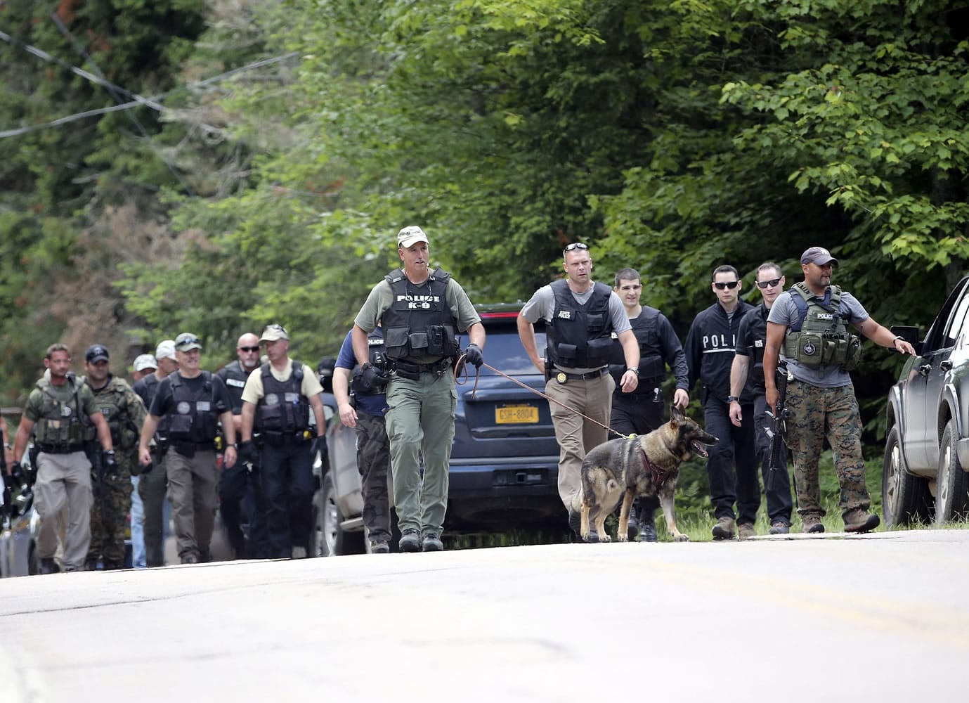 Officers walk along a road Monday as the search continues in Owls Head, N.Y., for two escaped prisoners from the Clinton Correctional Facility in Dannemora, N.Y.