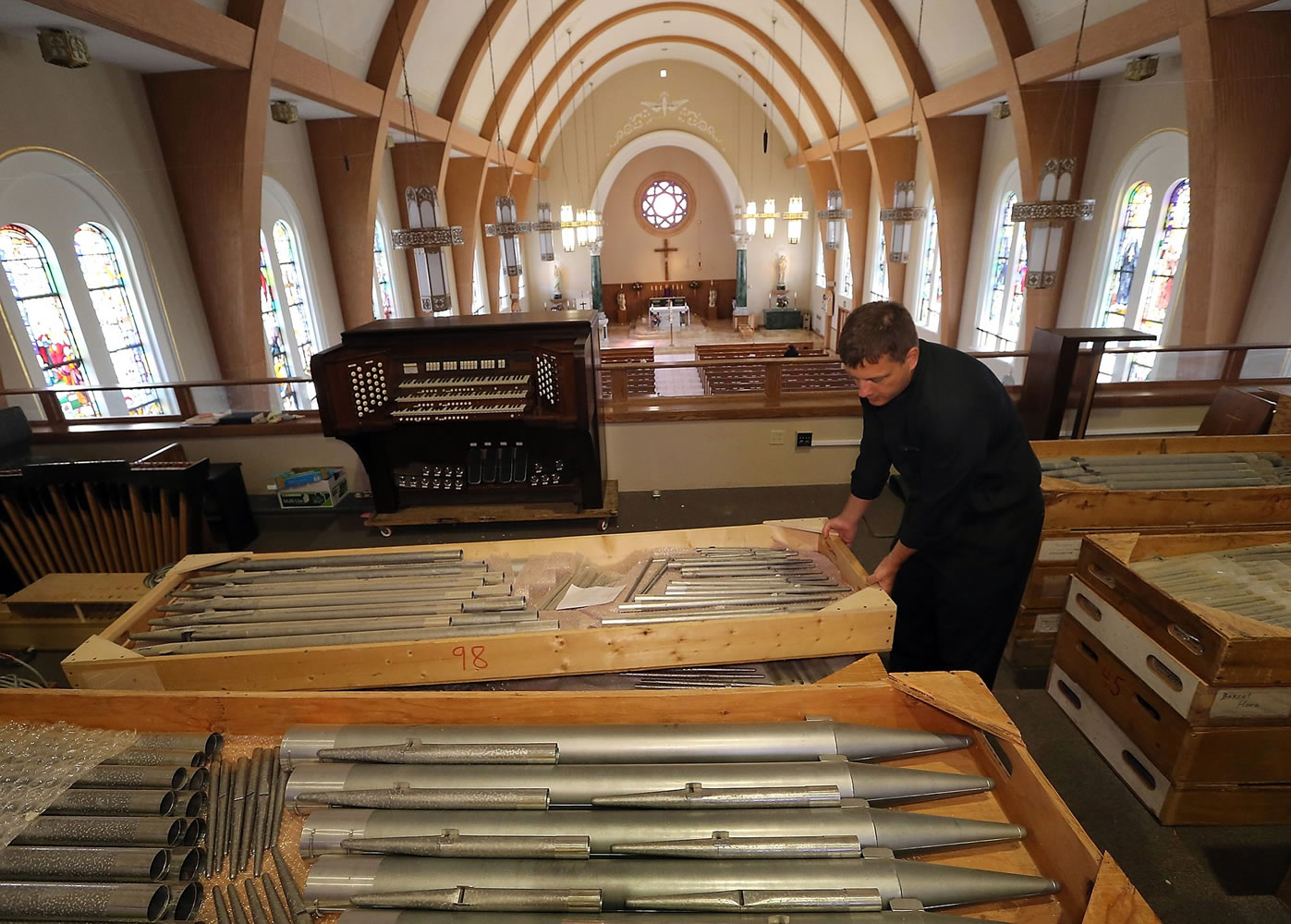 Father Derek Lappe takes a closer look at the boxes of various sized organ pipes that are being installed in the choir loft of Our Lady Star of the Sea in Bremerton.