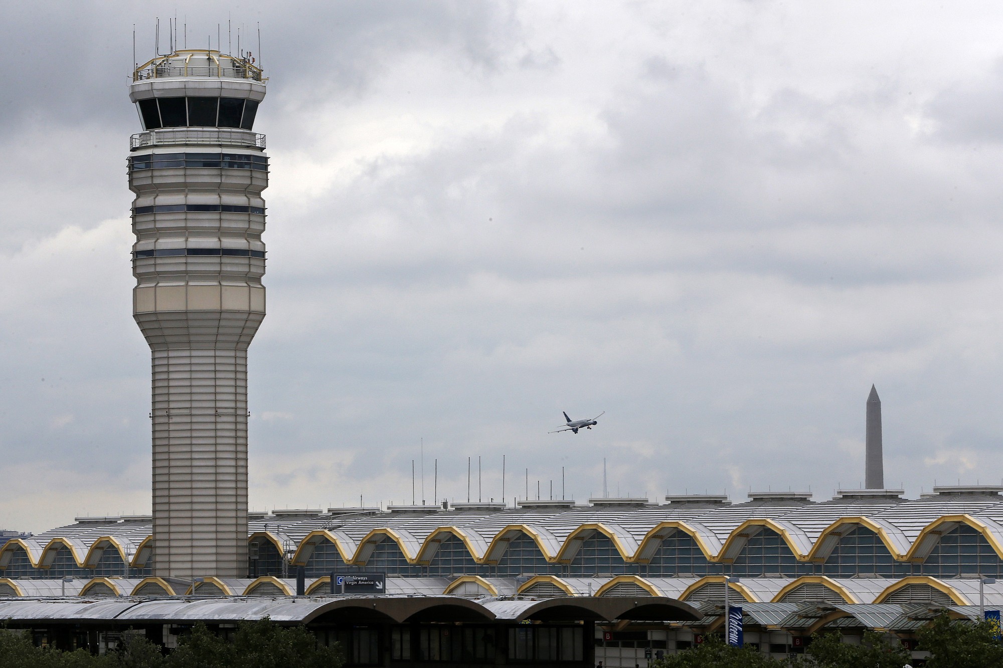 An airplane flies between the air traffic control tower and the Washington Monument on Monday at Washington's Ronald Reagan National Airport.