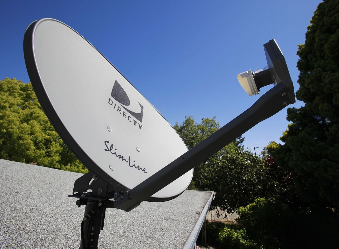A DirecTV satellite dish is attached to a roof at a home in Palo Alto, Calif.