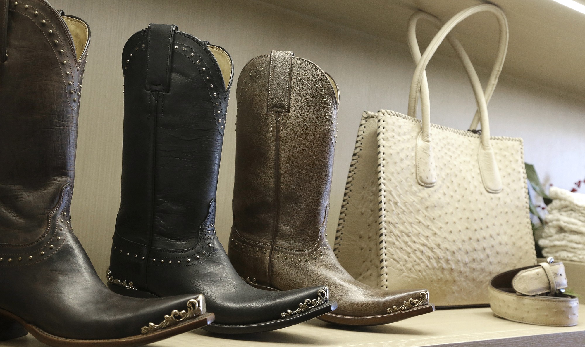 Western boots share shelf space with a purse and belt at the Lucchese Bootmaker shop in Houston.