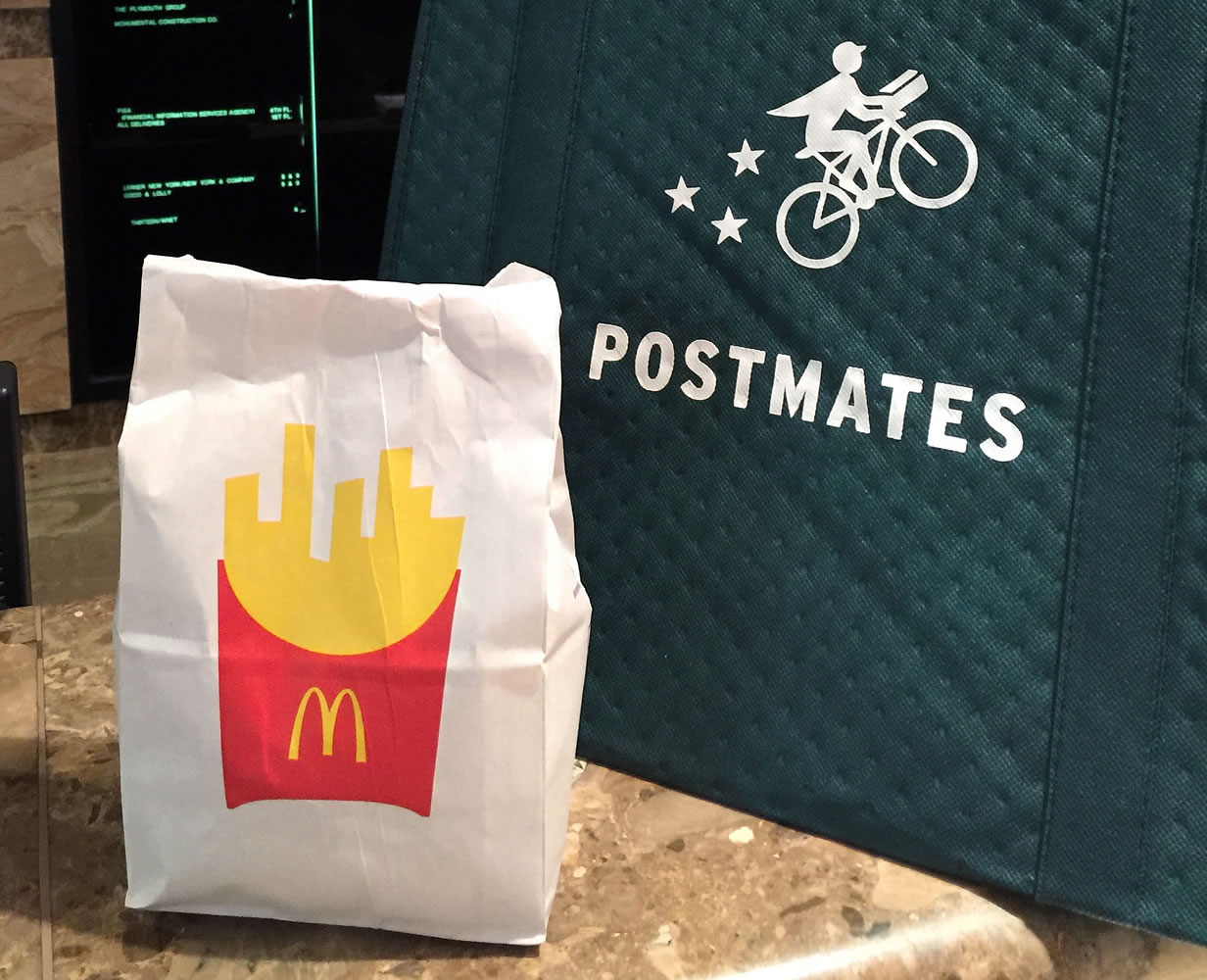 A bag of food from McDonald's ordered through the Postmates service sits next to a Postmates delivery bag during a delivery in New York on Wednesday.