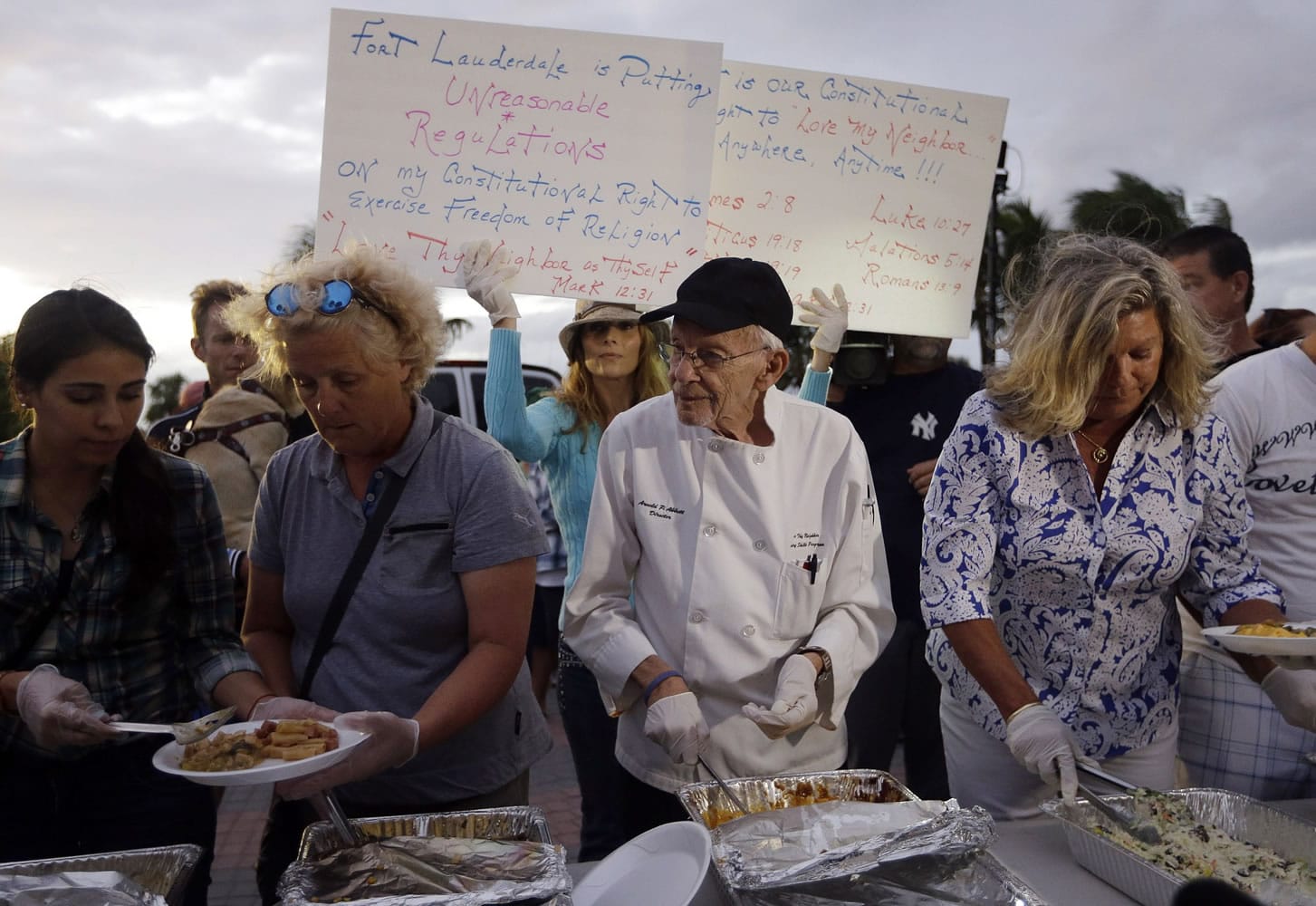 Homeless advocate Arnold Abbott, 90, director of the nonprofit group Love Thy Neighbor Inc., center, serves food to the homeless with the help of volunteers from a public parking lot next to the beach Wednesday in Fort Lauderdale, Fla.