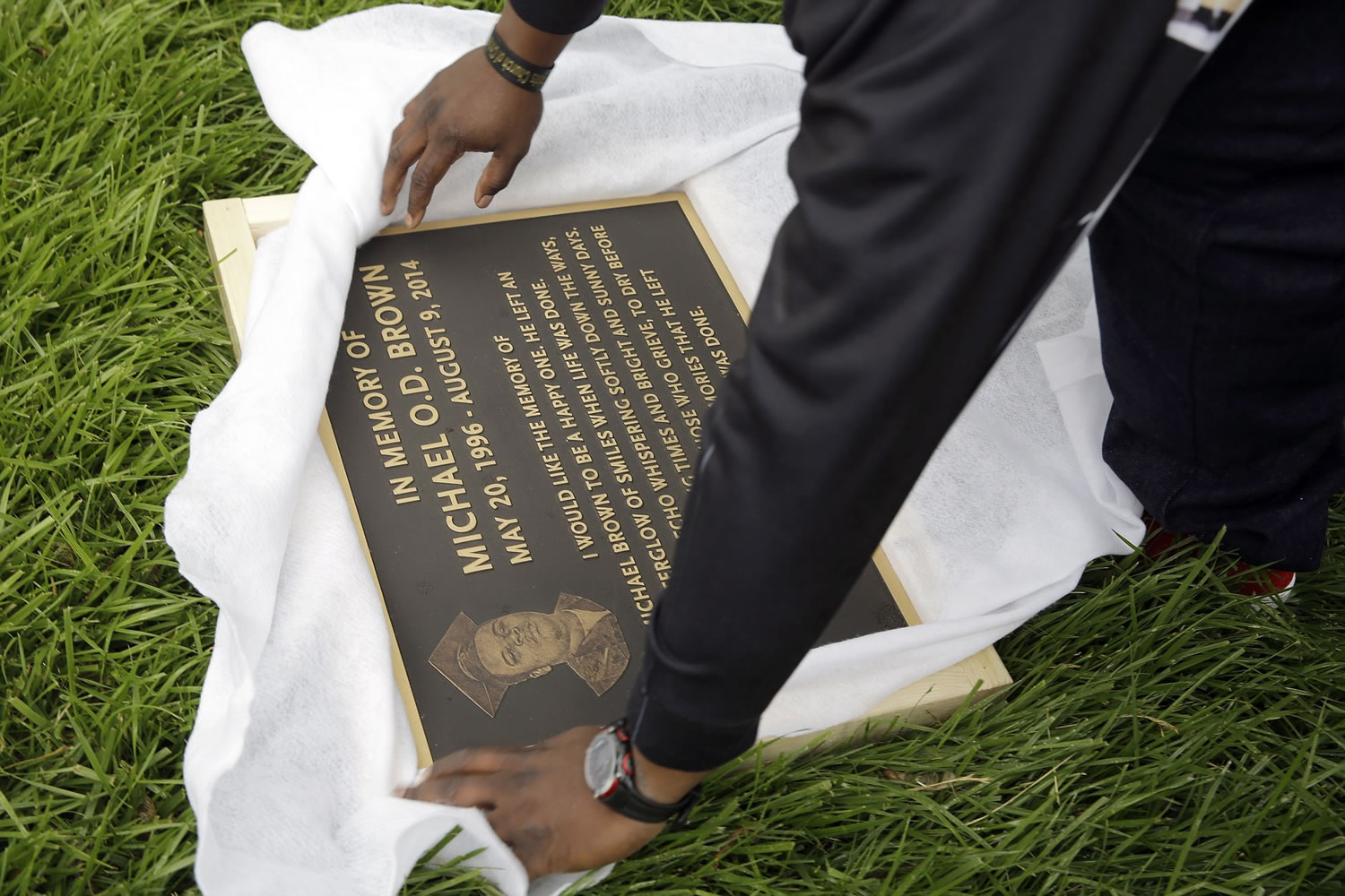 Michael Brown Sr. on May 20  unwraps a plaque remembering his son, Michael Brown, to show volunteers as they remove items left at a makeshift memorial to Michael Brown in Ferguson, Mo. The one year anniversary of the shooting of Michael Brown, which sparked months of nationwide protests and launched the &quot;Black Lives Matter&quot; movement, is on Sunday, Aug. 9.