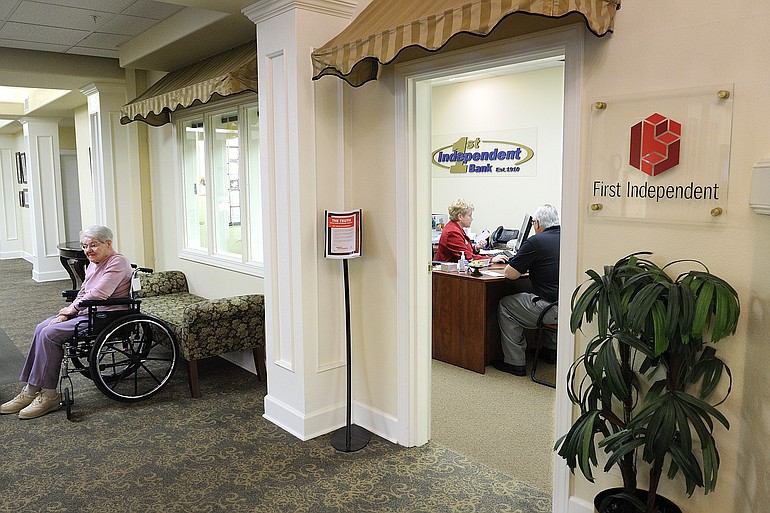 First Independent personal banker Karen Meisner, wearing red, helps Ellery Bennett at the bank's small branch at Touchmark at Fairway Village senior living community.