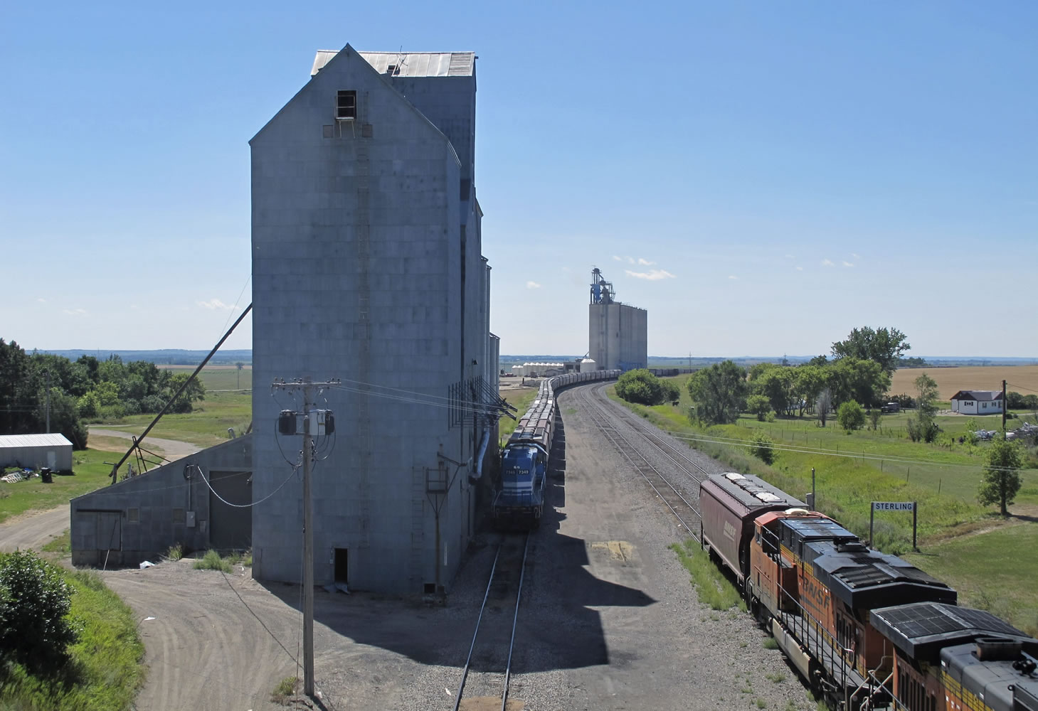 In this Aug. 20, 2015 photo, a mile-long grain train is loaded with more than 20 million pounds of spring wheat at an elevator in Sterling, N.D. With fall harvest fast approaching, farmers are expecting to get the trains they need to move crops to market, a turnaround from the past two years when elevators across North Dakota _ and in some other farm states _ were overflowing and mountains of grain were piled on the ground awaiting rail cars.