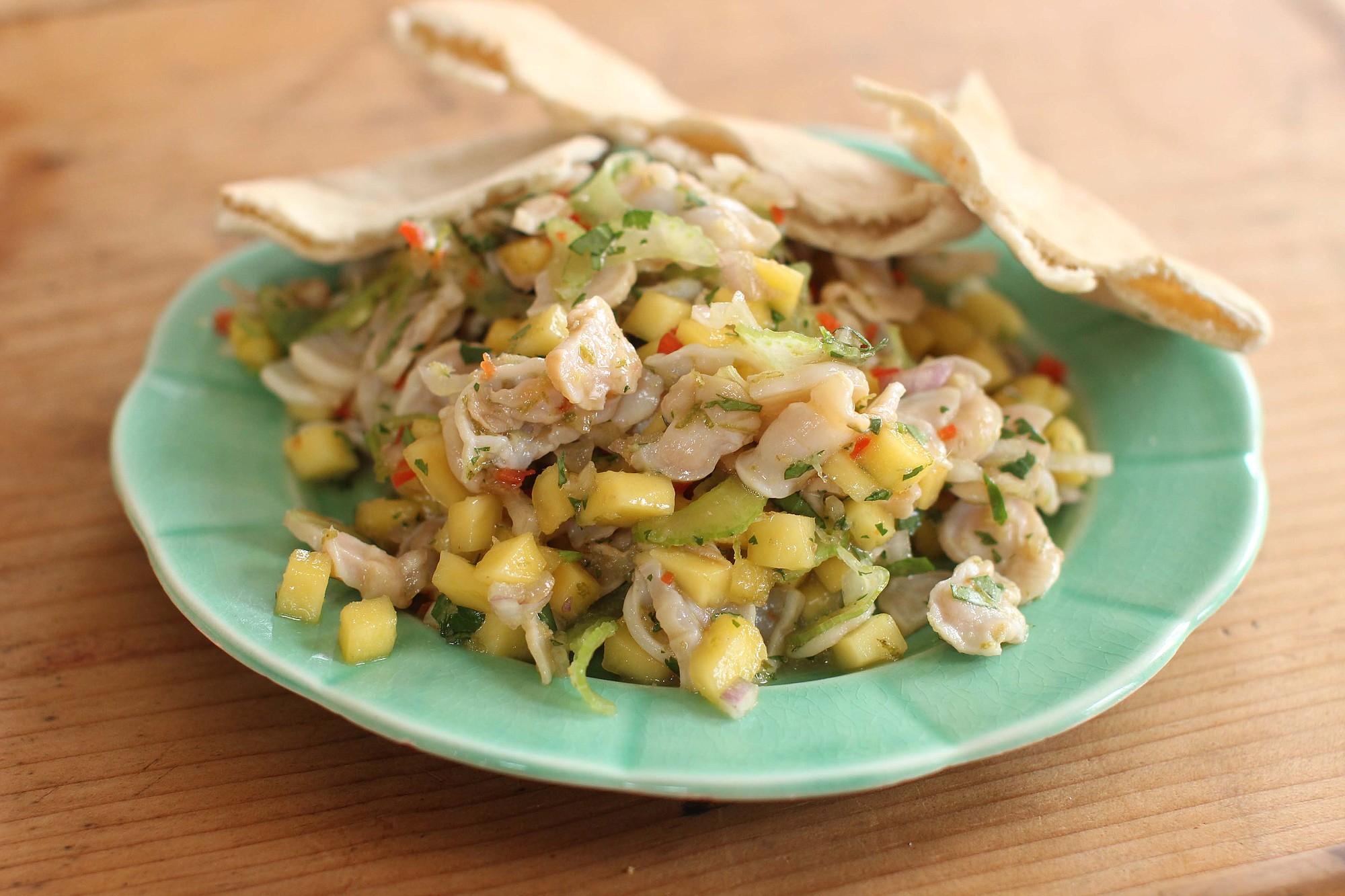Geoduck salad, made from geoduck clams, greens, mango and chilis and served on pita bread .