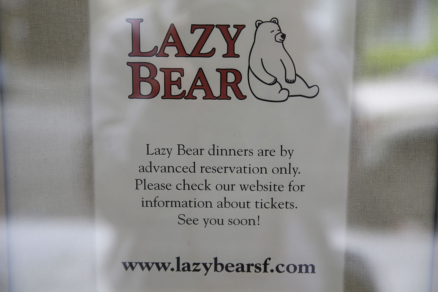 A sign in the front window explains how to purchase tickets to dine at the Lazy Bear restaurant in San Francisco.