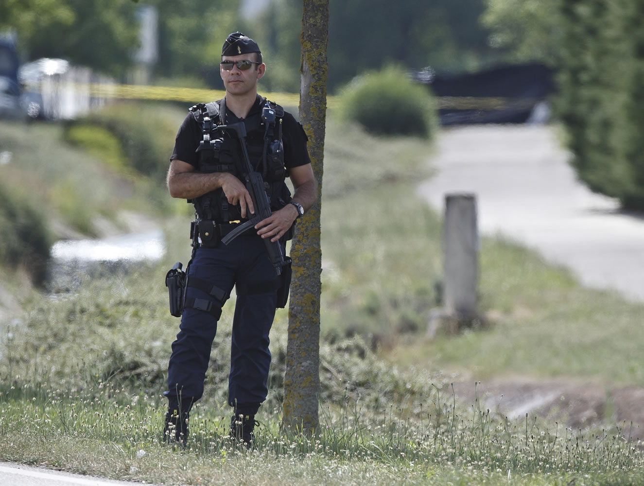 A police officer guards the road leading to a plant where an attack took place in Saint-Quentin-Fallavier, southeast of Lyon, France, on Friday.