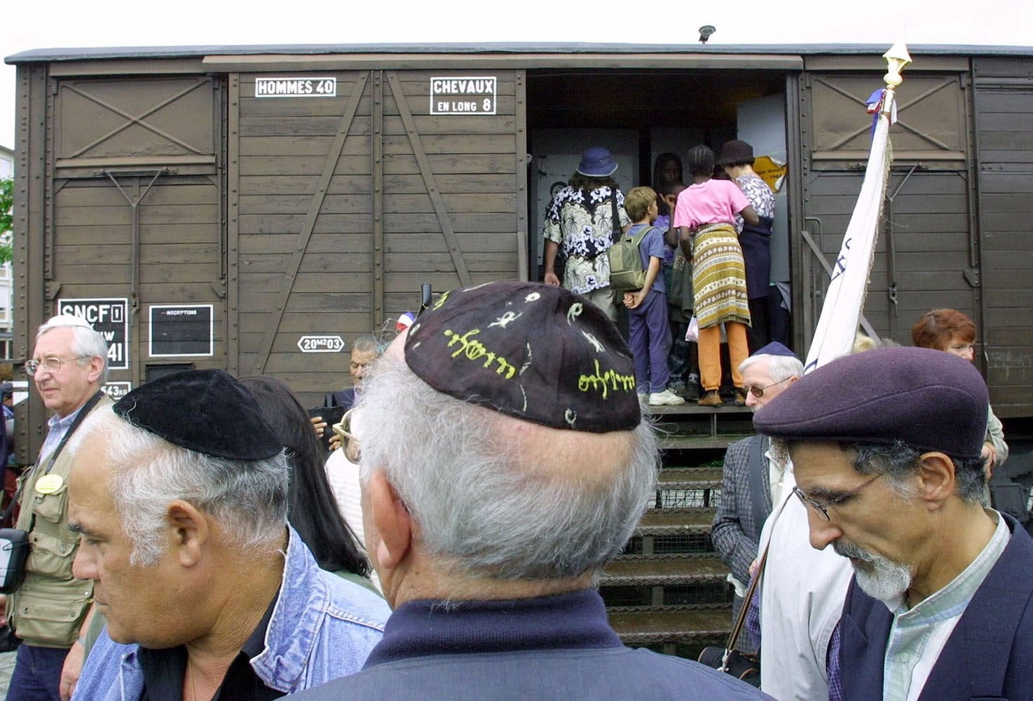 French Holocaust survivors gather Aug. 20, 2001, at the site of the former Drancy detention camp, north of Paris, France. From Aug. 20, 1941 until the end of World War II, more than 70,000 Jewish men, women and children passed through Drancy on their way to Nazi extermination camps, particularly Auschwitz. The wagon is part of the memorial site. Hundreds of Americans and others deported by France's state rail company SNCF during the Nazi occupation will be entitled to compensation under a new U.S.-French agreement. The French Foreign Ministry and U.S. State Department announced an accord Friday for a $60 million compensation fund, financed by France and managed by the United States. SNCF transported about 76,000 French Jews to Nazi concentration camps.