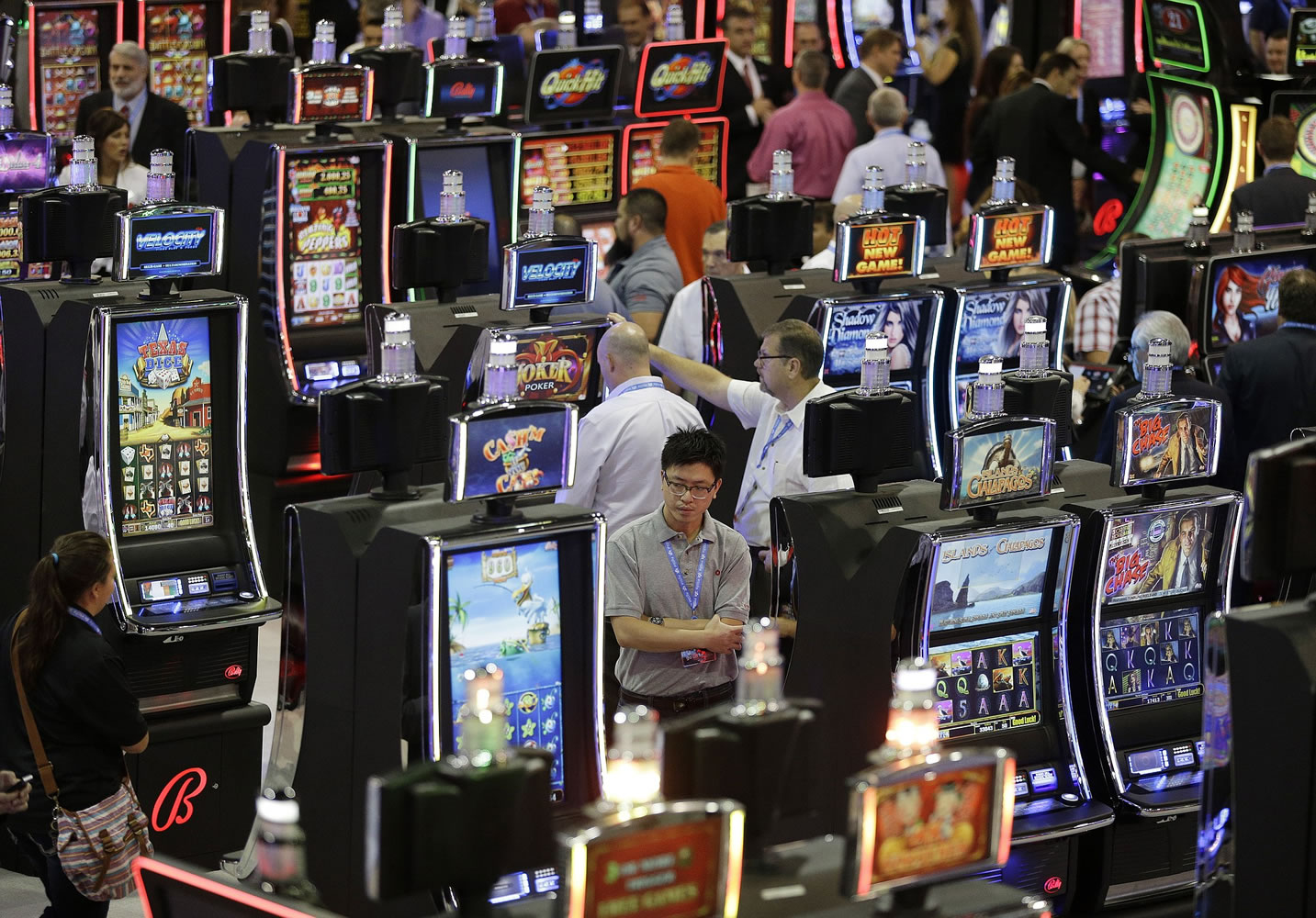 People look at slot machines at the Ballys Technology booth during the Global Gaming Expo Tuesday, Sept. 30, 2014, in Las Vegas. U.S. casinos and the makers of the games found inside had a $240 billion economic impact and employed 1.7 million people in 2013, a study shows. The American Gaming Association was expected to announce the results of the study Tuesday, Sept. 30, 2014.