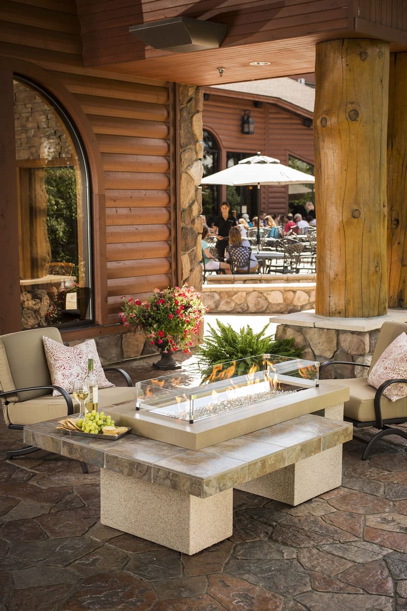A fire pit table with a plastic wind guard is the centerpiece of a seating area at Paradise Landing restaurant in Balsam Lake, Wis. Gas-fueled fire pit tables are becoming popular for their mood-setting entertainment and can extend the outdoor season three or more months in temperate areas. Round tables are said to be the No.