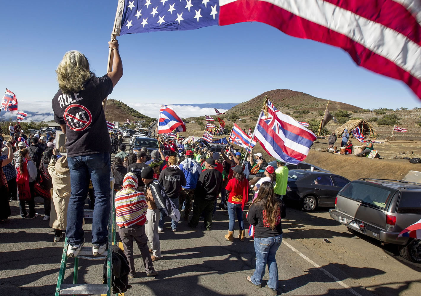 In this photo taken on Wednesday, June 24, 2015, Thirty Meter Telescope protesters walk on a road during the first of many blockades that started at the Mauna Kea visitors center, stopping TMT construction vehicles from driving up to the summit of the mountain, about 40 miles west of Hilo, Hawaii. Hundreds of protesters on the Hawaii mountain road erupted in cheers Wednesday after construction crews turned around and retreated from the site for what would be one of the world's largest telescopes.