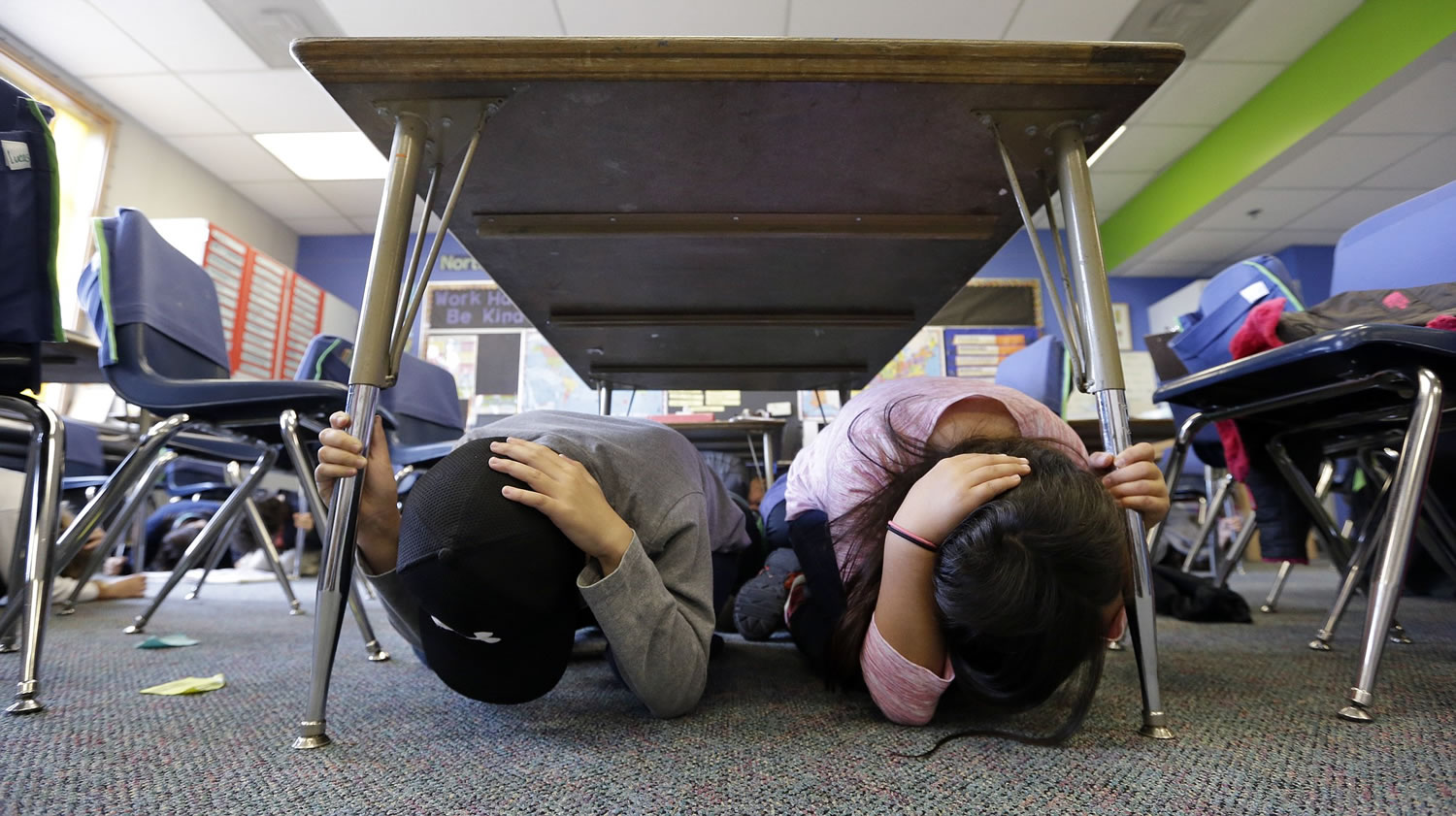 Fourth-graders huddle under a desk Thursday during the Great Washington Shakeout drill at West Woodland Elementary School in Seattle. Thousands of students across the state practiced ducking under desks in the coordinated drill.