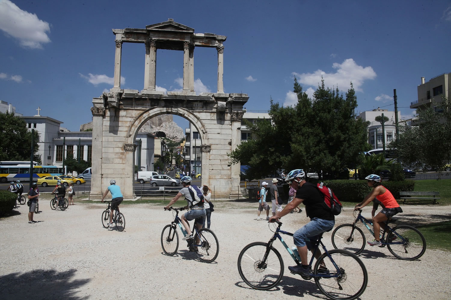 Tourists ride bicycles next to Andrian's Arch in Athens on Tuesday.