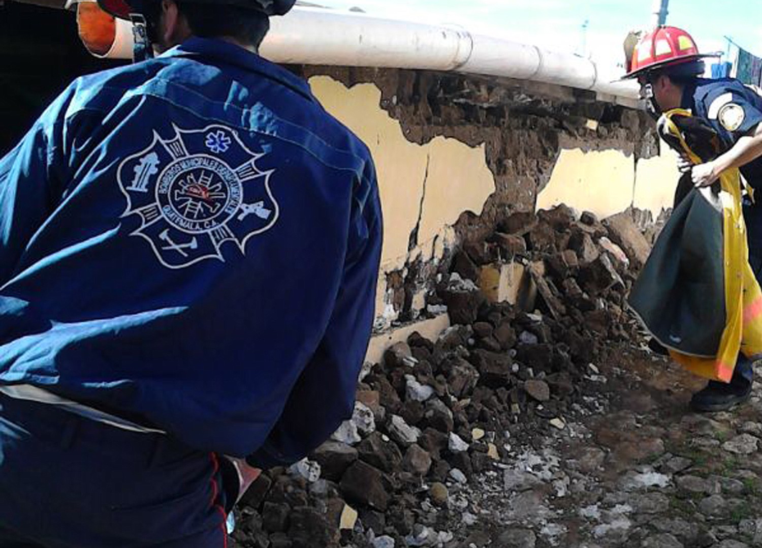 Firefighters check a home that collapsed during an earthquake in San Pedro, Guatemala, on Monday.