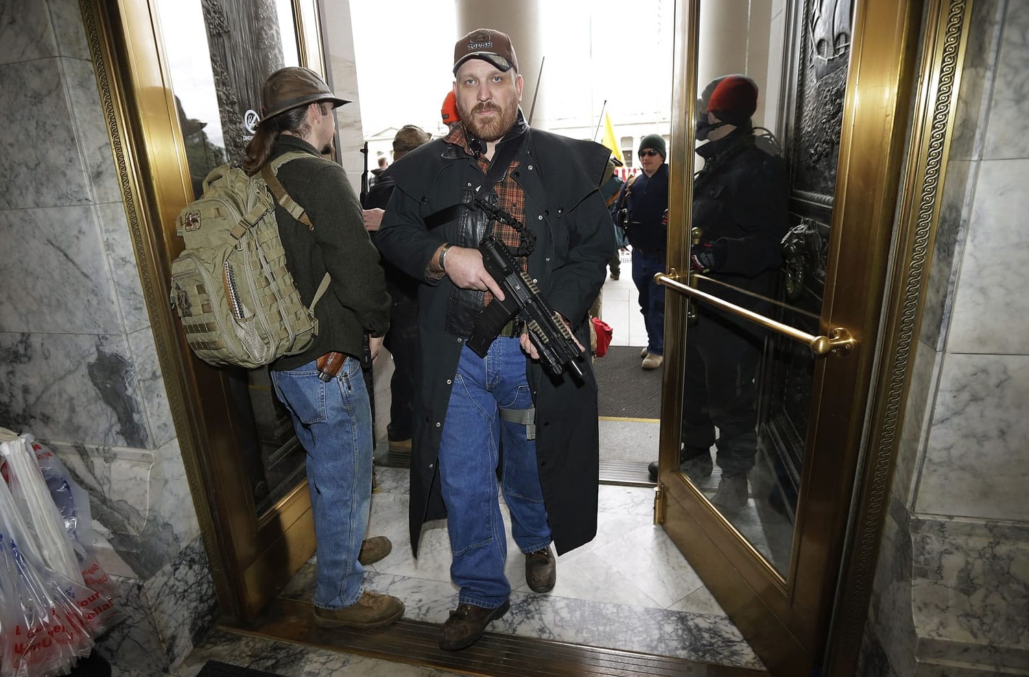 Jason McMillon carries his Rock River LAR-PDS pistol with a 45-round magazine into the Legislative Building at the Capitol in Olympia, Wash., Thursday, Jan. 15, 2015, during a gun-rights rally opposing the state's Initiative 594, which requires - with only a few exceptions - background checks on all gun sales and transfers. Rules at the Capitol allow guns to be carried openly in the building. (AP Photo/Ted S.