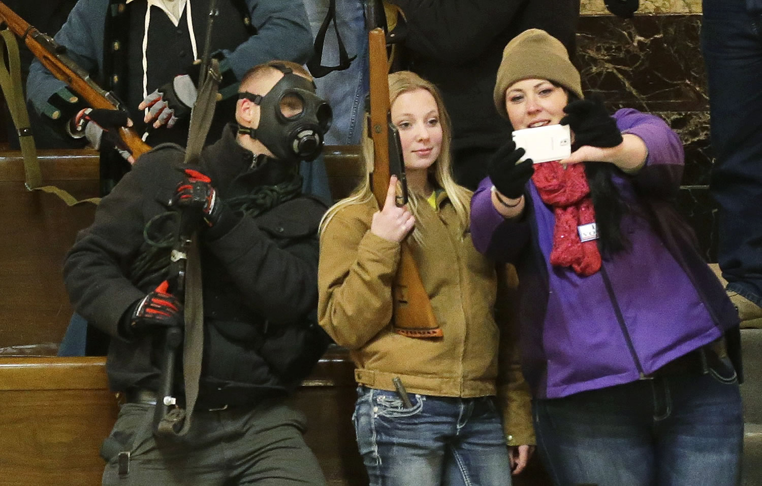 Gun owners, including Garrett Bosworth, 16, center, of Yakima, pose for a selfie as they display their weapons in the upper gallery of the House chambers on Thursday.
