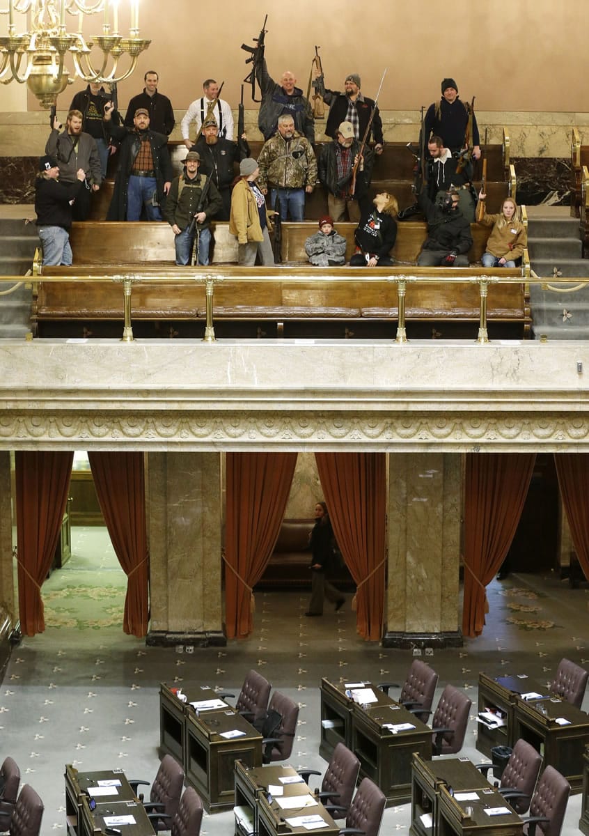 Gun owners display their weapons in the upper gallery of the House chambers, Thursday, Jan. 15, 2015, at the Capitol in Olympia, Wash. The House was not in session when this photo was taken, and members of the group went to the gallery following a protest outside the Legislative building in opposition to the state's Initiative 594, which requires - with only a few exceptions - background checks on all gun sales and transfers. (AP Photo/Ted S.