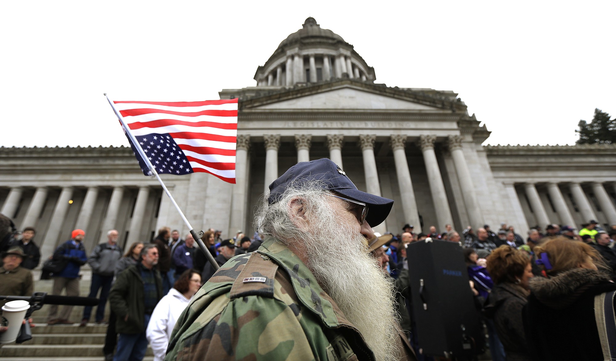 Dave &quot;Doc&quot; Brown, of Tumwater, Wash., displays an upside-down American flag in the barrel of his M1 carbine gun, Thursday, Jan. 15, 2015, during a gun-rights rally at the Capitol in Olympia, Wash. The rally was held to oppose the state's Initiative 594, which requires - with only a few exceptions - background checks on all gun sales and transfers. (AP Photo/Ted S.