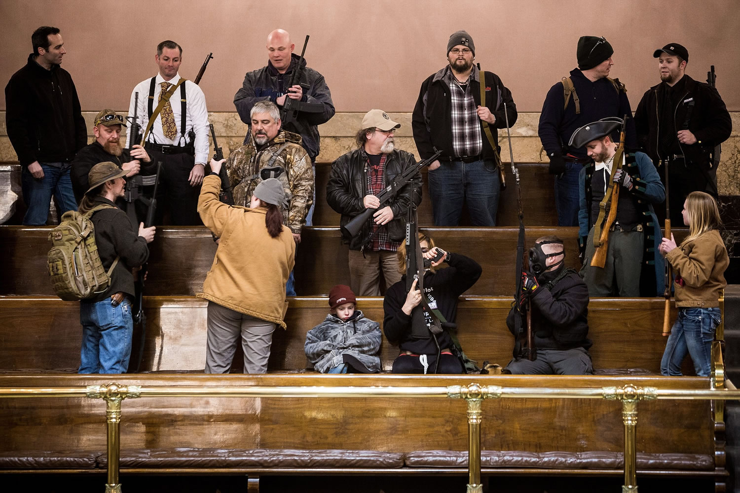 Demonstrators with weapons file into the pews of the House Gallery on Thursday to demand support to reverse Initiative 594 during a rally in the Capitol building in Olympia. The lieutenant governor announced Friday that open carry of guns has been banned in the Senate's public viewing area. No decision has been made on openly carrying guns in the House's public gallery.