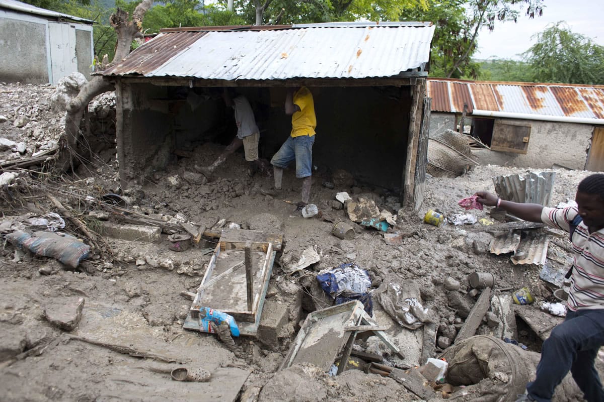 Residents salvage personal items after a mudslide triggered by Tropical Storm Erika left it partially submerged, in Montrouis, Haiti, Saturday, Aug. 29, 2015. Erika dissipated early Saturday, but it left devastation in its path on the small eastern Caribbean island of Dominica, and parts of Haiti, authorities said.