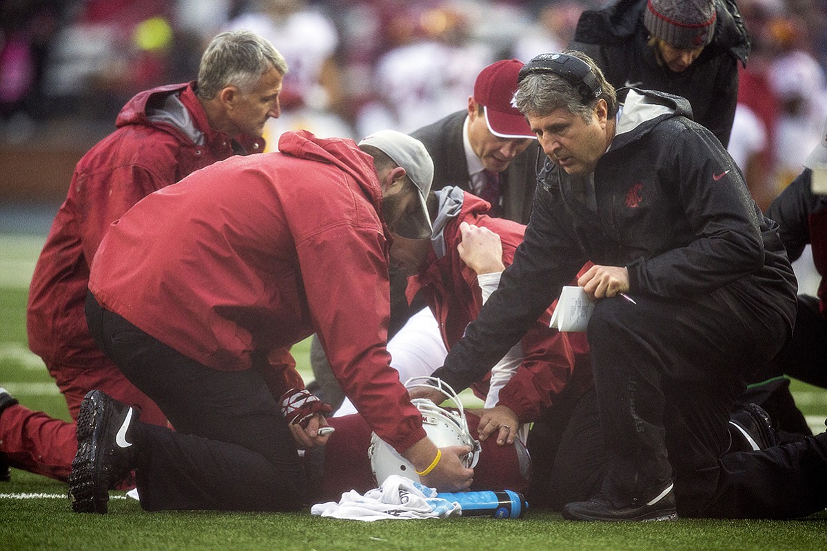 Washington State head coach Mike Leach comforts quarterback Connor Halliday, center, as team physicians and trainers attend him during the first quarter of an NCAA college football game Saturday, Nov. 1, 2014, at Martin Stadium in Pullman. Leach said Monday that Halliday suffered a broken ankle, ending his college career.