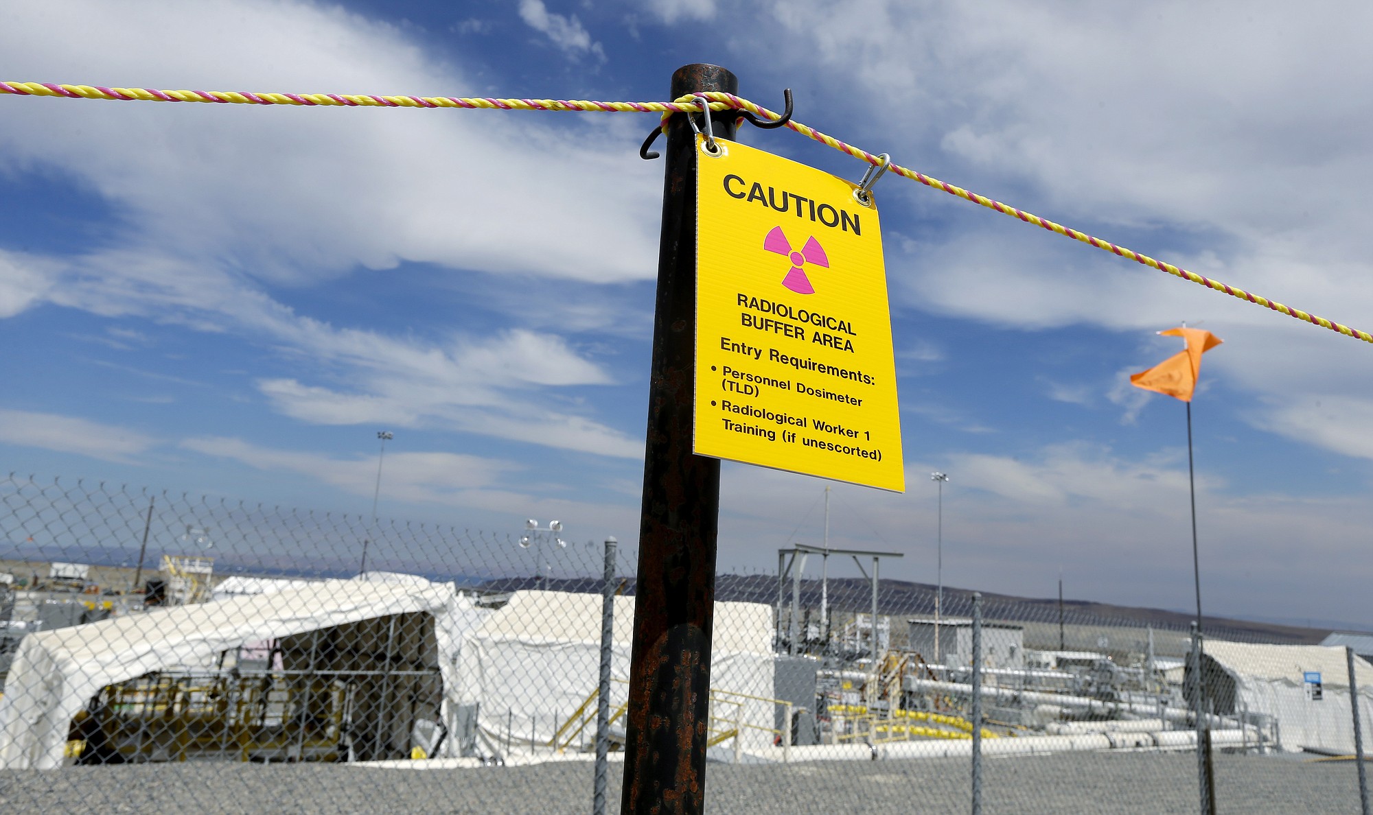A sign warns of radioactivity near a wind direction flag indicator at the &quot;C&quot; tank farm during a media tour of the Hanford Nuclear Reservation Wednesday, July 9, 2014 near Richland, Wash. Officials said Wednesday that 12,000 air samples taken at Hanford this year after more than three dozen workers reported being sickened by chemical vapors have failed to find a cause for the problem. (AP Photo/Ted S.