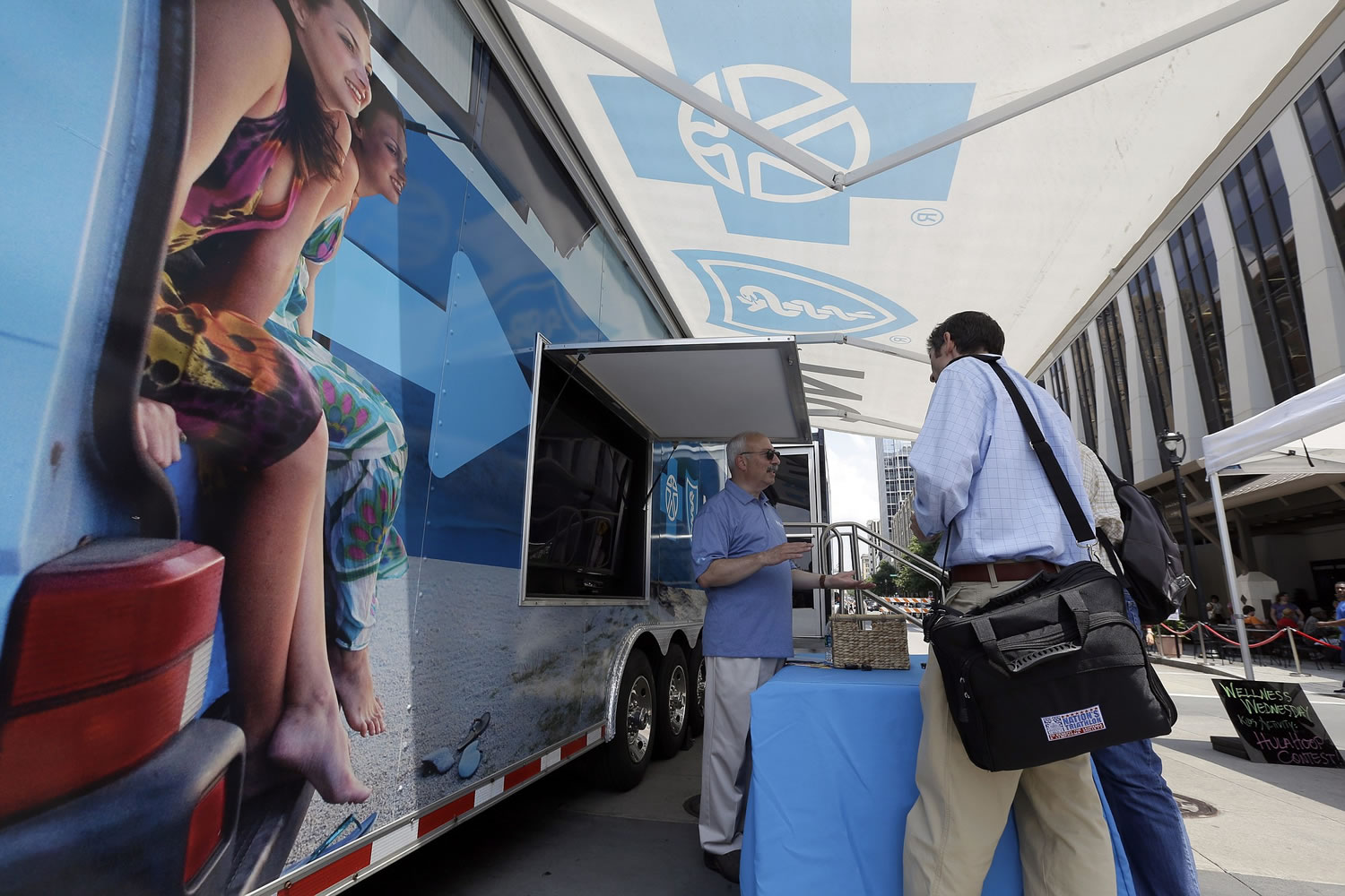 Blue Cross Blue Shield of North Carolina employee Lew Borman, left, helps a customer outside a trailer at the downtown farmer's market in Raleigh, N.C.